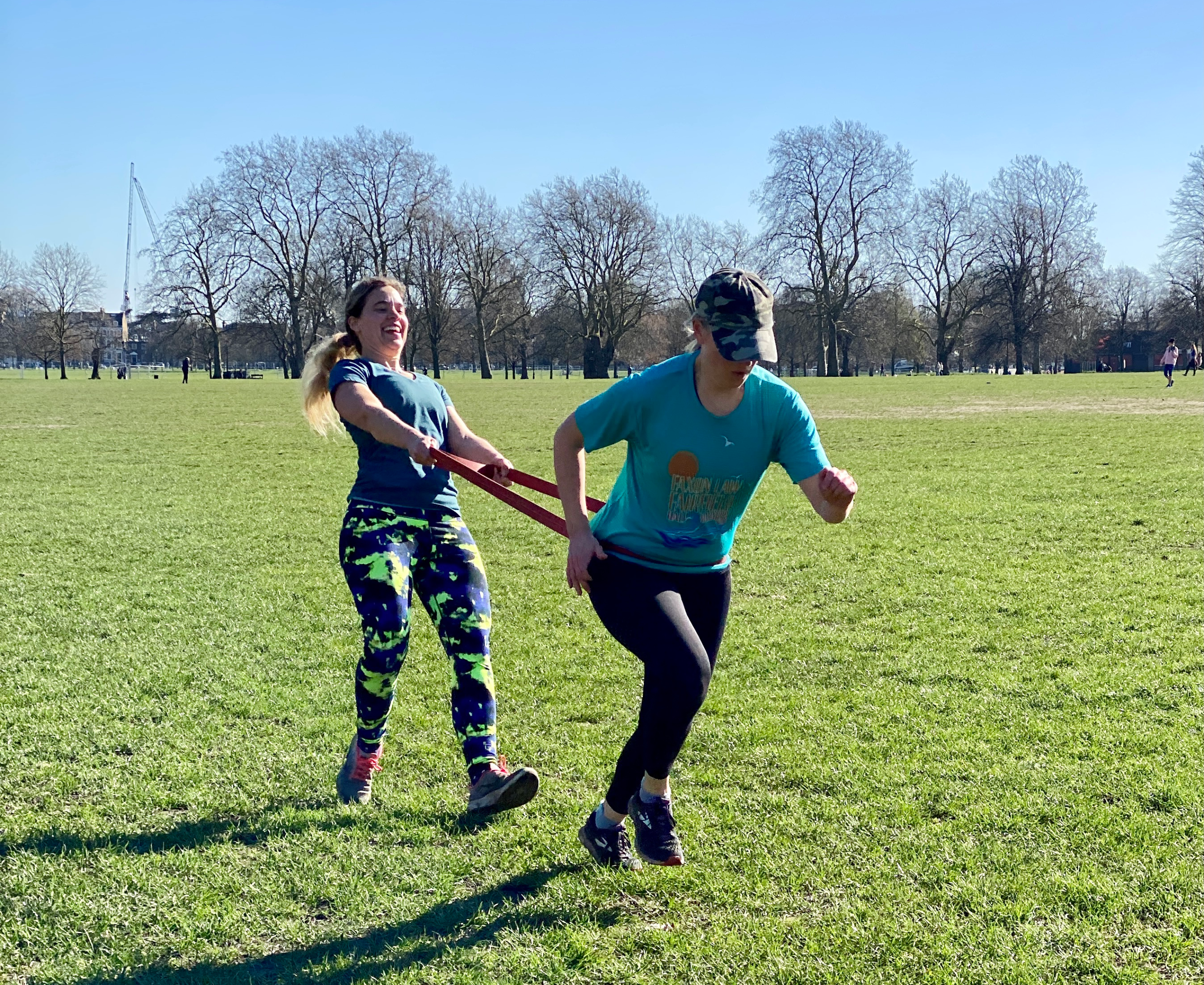 Two mums running with resistance band during outdoor fitness class in Clapham Common London