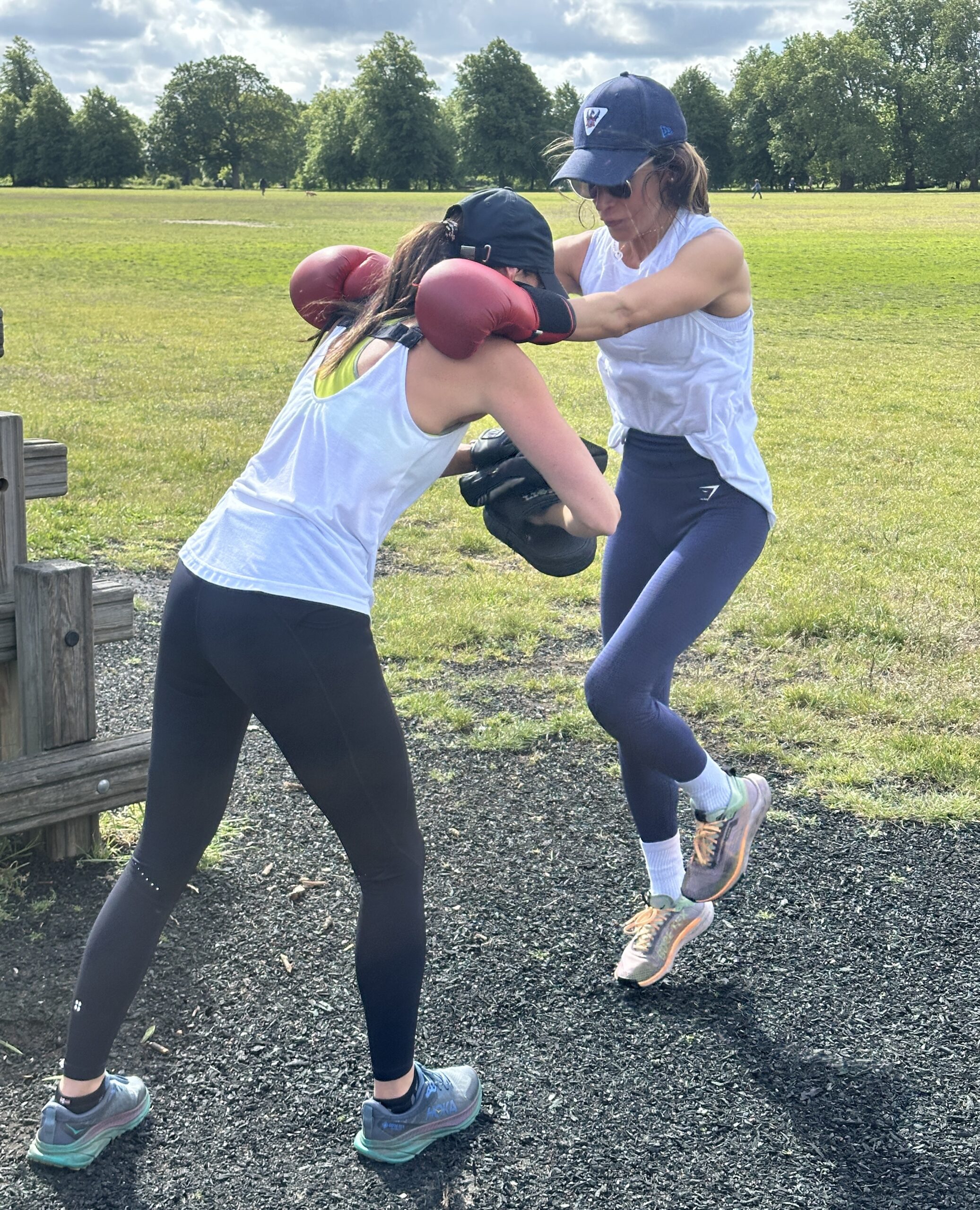Two mums doing boxing and kick exercises during an outdoor fitness class in Clapham Common